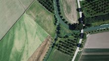 Luchtfoto van landschap met weilanden, een rivier en een weg